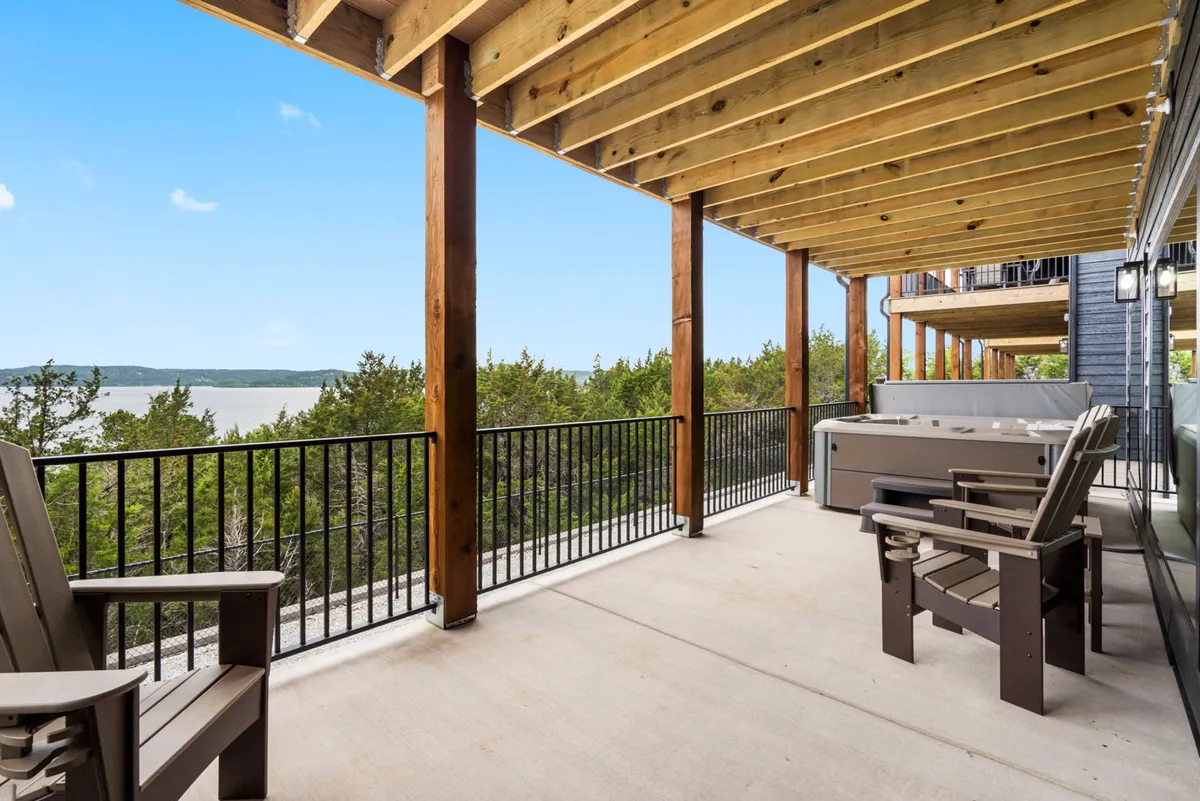 This exterior shot captures a cozy hot tub overlooking a tranquil lake, framed by wooden beams and surrounded by Adirondack chairs. The natural setting and water views evoke relaxation and the outdoor lifestyle that the section highlights.
