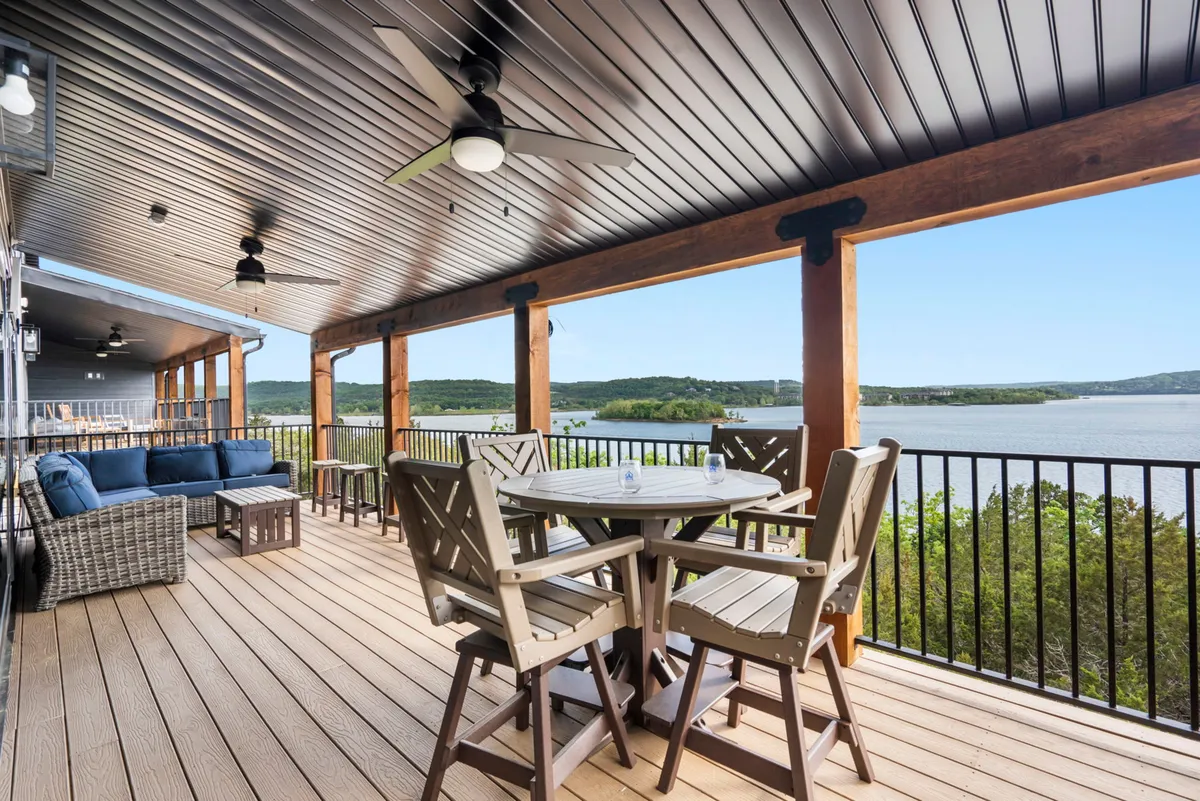 The image showcases a spacious deck overlooking stunning, uninterrupted views of Table Rock Lake. The deck features comfortable seating and a large dining table, inviting guests to relax, dine, and soak in the serene lakeside atmosphere. The scene evokes feelings of tranquility and togetherness, perfect for enjoying sunsets, outdoor meals, and quality time with friends and family.
