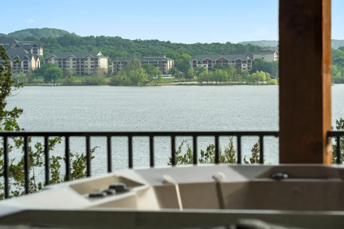 An outdoor hot tub set on a deck facing a serene lake and wooded hillsides. The scene exudes relaxation, with the hot tub serving as a luxurious post-game retreat and the expansive view creating a tranquil, restorative environment.