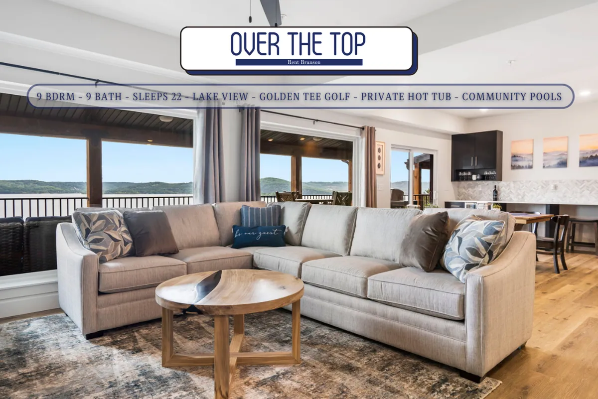 A spacious living room with a comfortable sofa and coffee table, positioned to highlight a wall of windows that offer expansive, unobstructed views of Table Rock Lake. The natural light pours in, creating an inviting space for relaxation and group gatherings. The decor is warm and welcoming, emphasizing the lake-centric design of the space.
