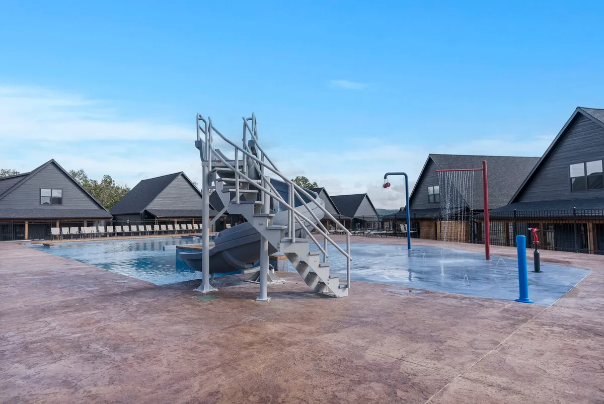 A vibrant outdoor swimming pool with a water slide and basketball hoop, surrounded by lounging areas. The pool area radiates fun and relaxation, suggesting recreational opportunities for teams to unwind together after a day of meetings or workshops.